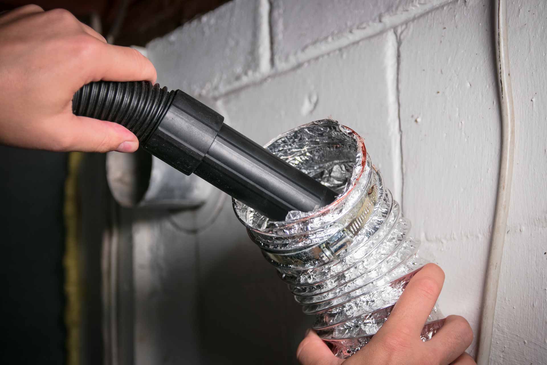 Appliance repair technician vacuum cleaning a dryer vent