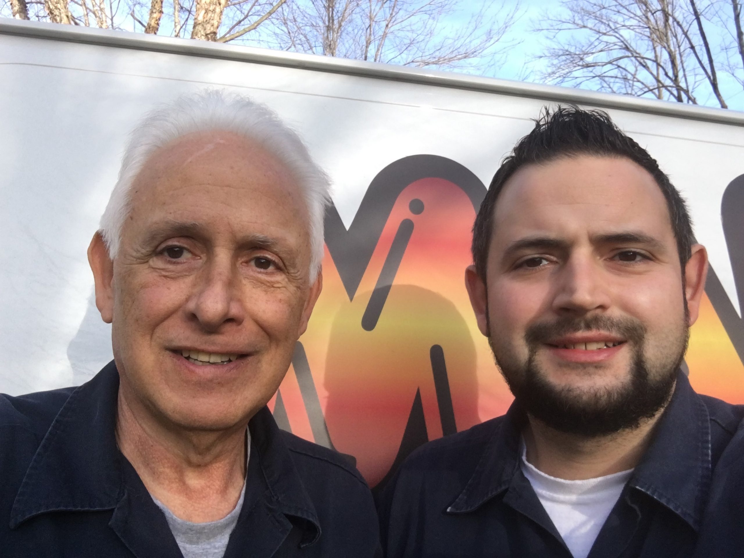 Appliance repair technicians from Manton Appliance Service smiling in front of the company van