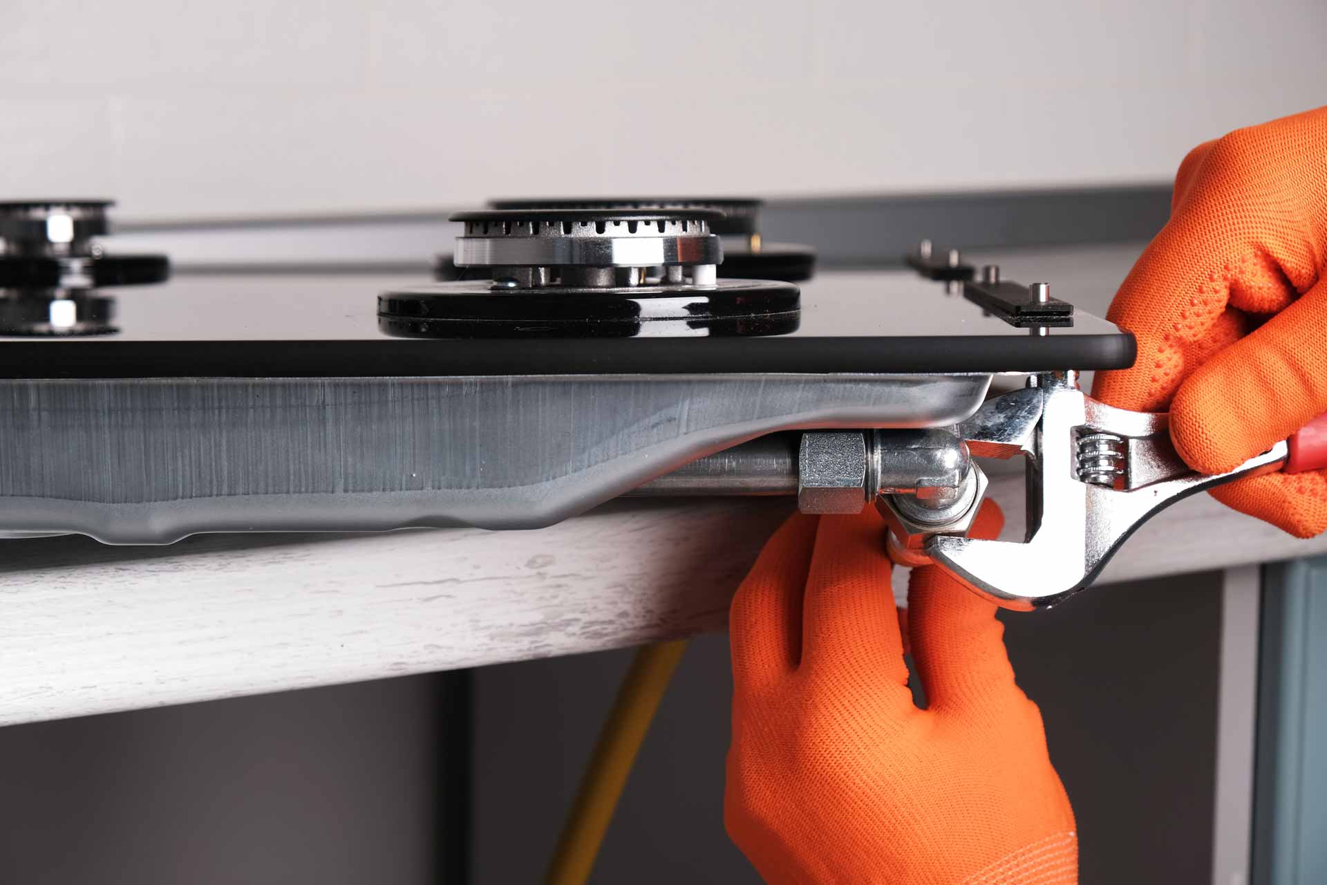 Technician with orange gloves repairing a gas stove