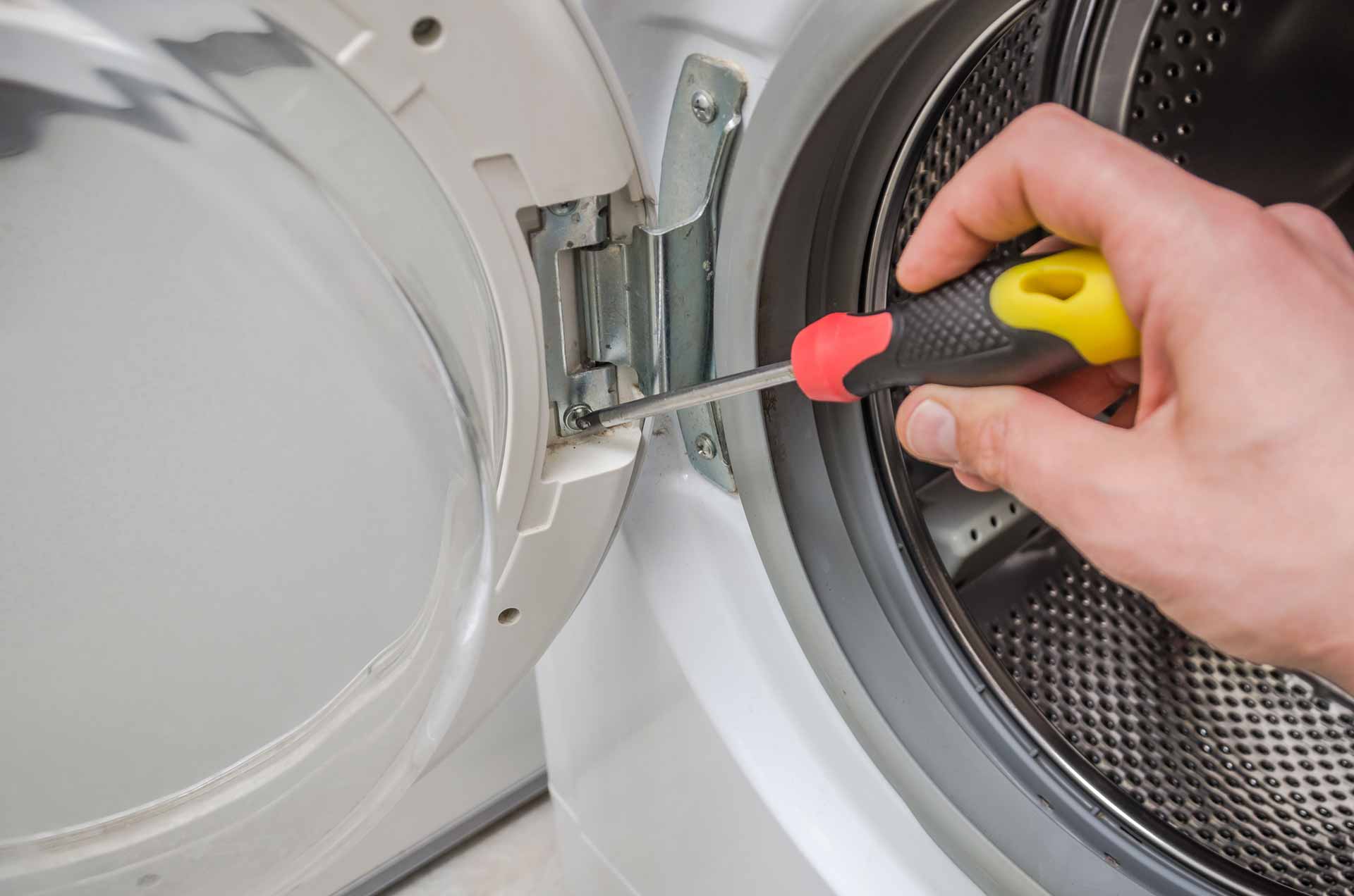 Appliance repair technician removing the door from a washing machine to facilitate a repair